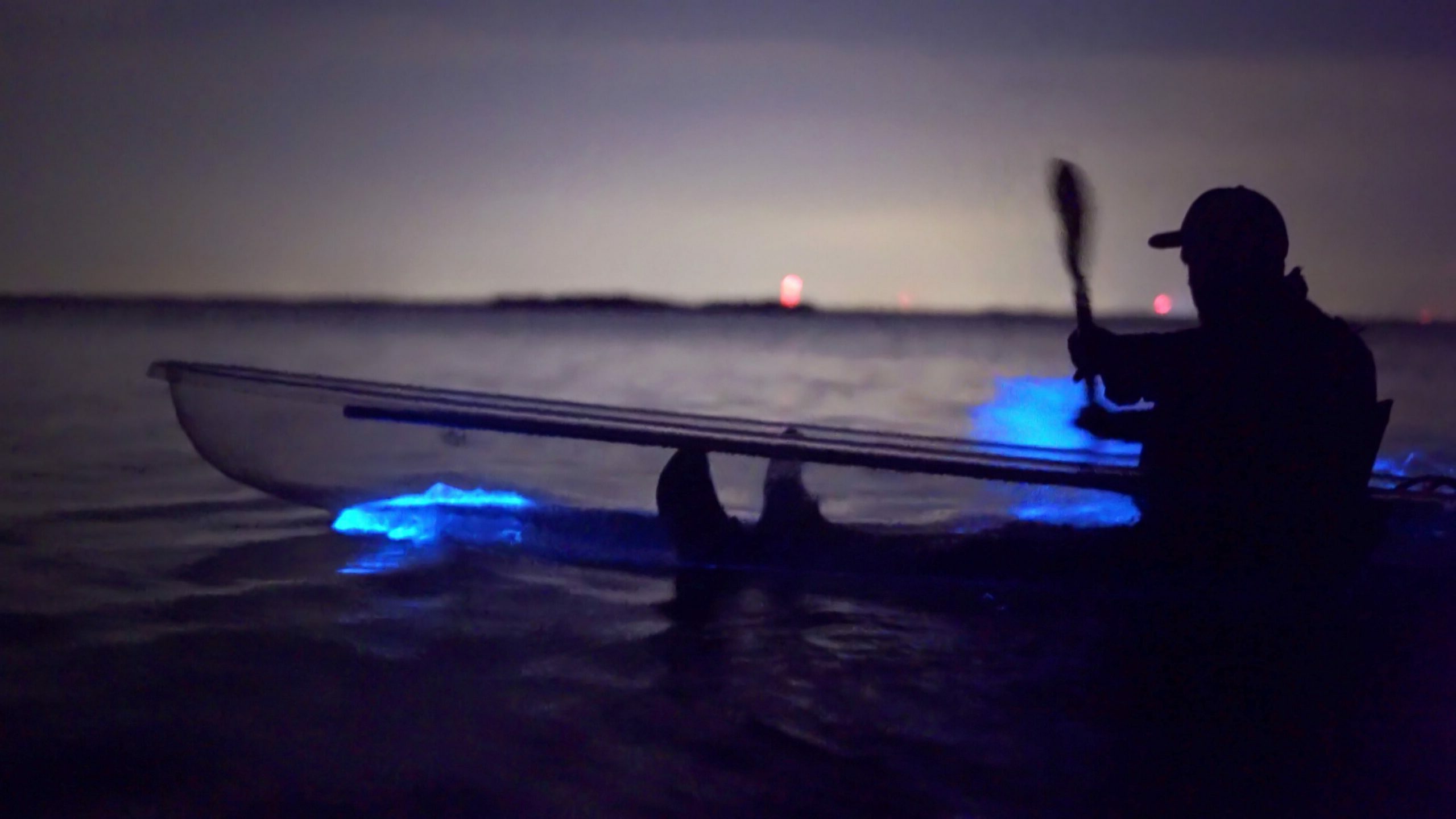 Someone paddling a Clear kayak during a bioluminescence kayak tour from Cocoa beach.